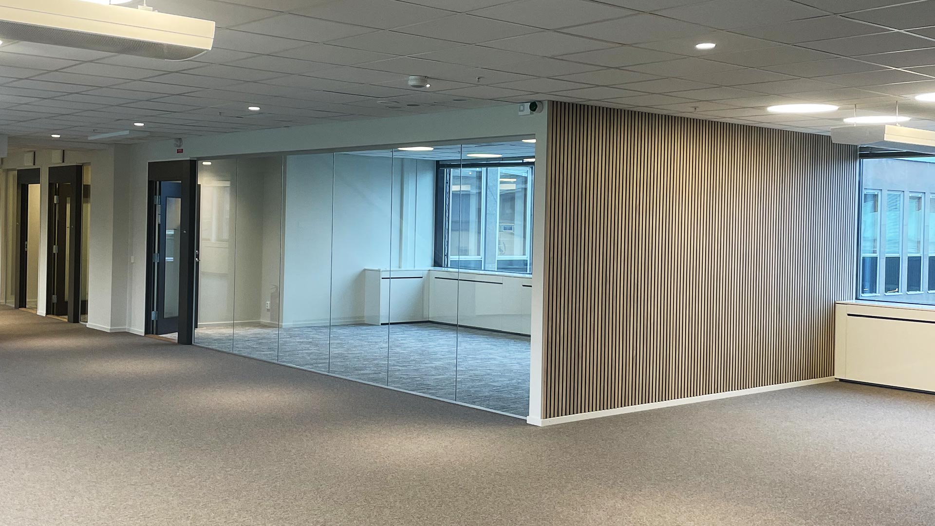 Modern kontorsinredning med glasväggar och träpaneler