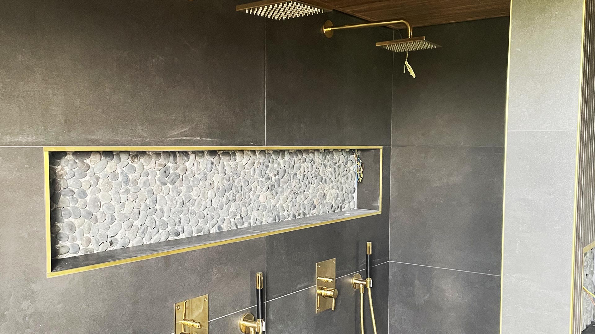 Lyxigt badrum med mörka plattor och mässingsdetaljer